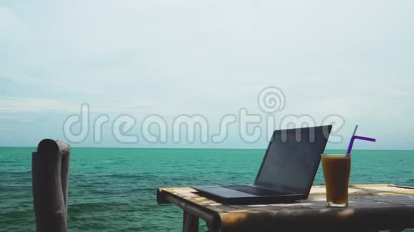 现代笔记本电脑放在热带海洋旁边的桌子上数字游牧在泰国亚洲远程工作和自由职业概念商务视频的预览图