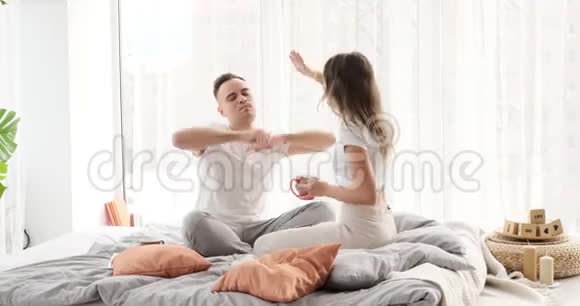 快乐的一对夫妻在家里的床上跳舞视频的预览图