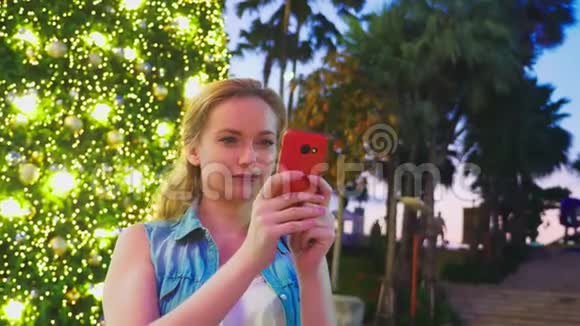 热带城市圣诞树和棕榈树背景下的快乐女人新年旅行的概念视频的预览图
