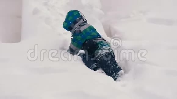 在一栋多层建筑的院子里下雪时男孩爬在雪地里的木滑梯上视频的预览图