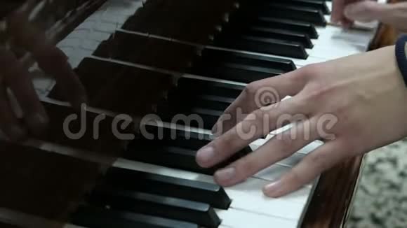 那个人弹钢琴一个年轻人的手按着乐器的白键和黑键一位年轻的钢琴家视频的预览图