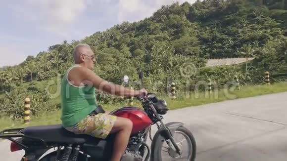 成熟的人骑摩托车在热带自然景观上旅行驾驶摩托车的老人视频的预览图
