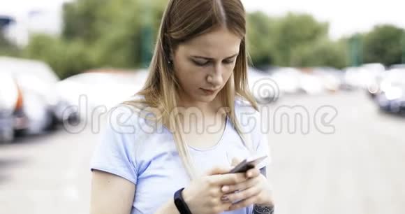 一位可爱的年轻女士正在户外的智能手机上输入一条信息视频的预览图