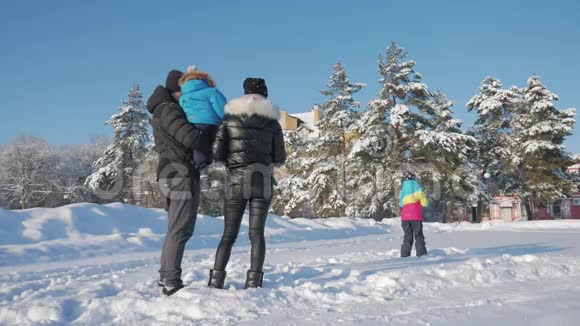 父亲母亲和两个孩子在大自然中玩着雪冬散步在户外快乐的家庭视频的预览图