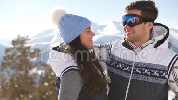 快乐的一对在滑雪场的背景下冬天的山脉拥抱和调情视频的预览图