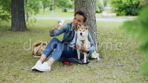漂亮的年轻女孩博主在城市公园里和纯种狗在户外自拍拥抱和抚摸美丽的女孩视频的预览图