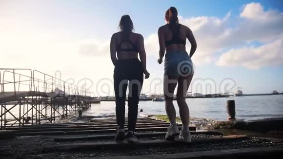 意大利索伦托的一个海港两名年轻女子在岩石上向大海慢跑视频的预览图