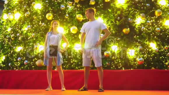 快乐的一对男女在热带城市圣诞树的背景下跳舞新年的概念视频的预览图