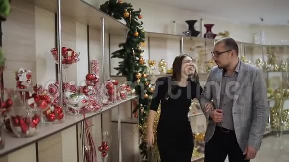 这对相爱的夫妇在超市挑选圣诞装饰品一个女人在考虑圣诞舞会视频的预览图