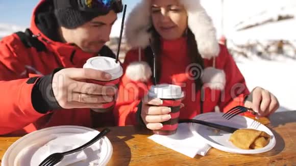 两个滑雪者在山顶上休息和吃饭一对夫妇在外面的滑雪场喝酒吃午饭视频的预览图