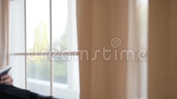 一个年轻人坐在扶手椅上翻过一本关于窗户背景的书视频的预览图