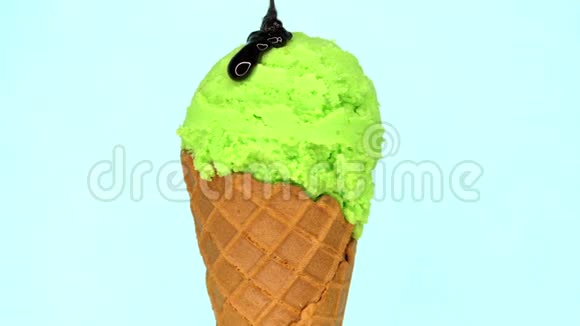 在蓝色背景上旋转的华夫饼锥中的活塞冰淇淋和液体巧克力浇在上面美味可口视频的预览图