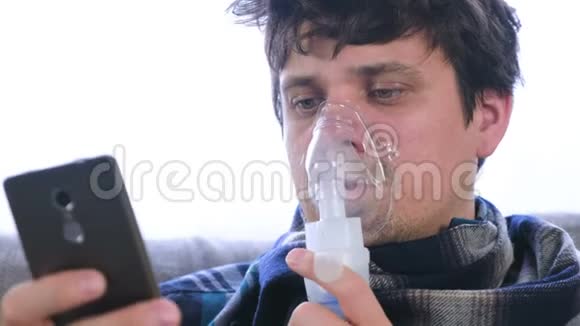 使用雾化器和吸入器进行治疗病人透过吸入面罩吸入并坐着看手机视频的预览图