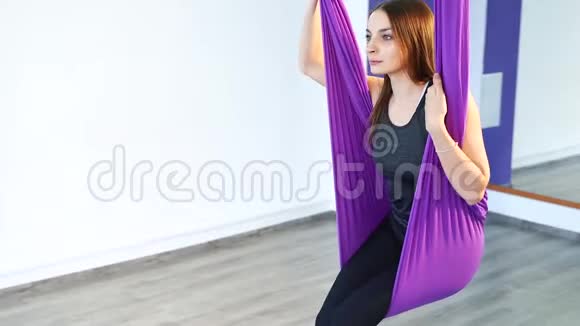 一位年轻女子在吊床上练习反重力瑜伽的肖像视频的预览图