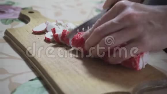 女人把螃蟹棒切在木板上然后把它倒入平底锅特写视频的预览图