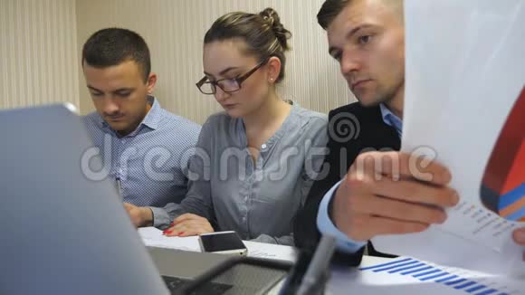 一群年轻的商人坐在现代办公室的桌子上从事新的项目同事仔细检查视频的预览图
