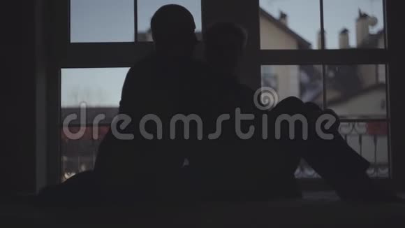一对年长夫妇在黑暗中的剪影背景是一扇宽阔的窗户女人和男人拥抱在一起抚摸在一起视频的预览图