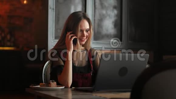 女人手拿着白色手机在桌子上办公室里有一台笔记本电脑视频的预览图