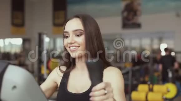 一位年轻的黑发女子在健身馆从事运动模拟器的肖像视频的预览图