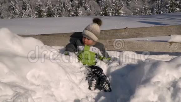 冬天小可爱的男孩在外面的雪地里玩耍背景是一片雪林这个男孩很高兴慢慢视频的预览图
