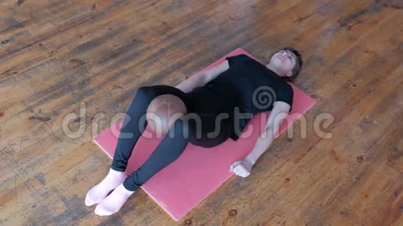 身体反射生活方式健身运动一个运动的女孩躺在粉红色的地毯上屏住呼吸把球拿在她视频的预览图