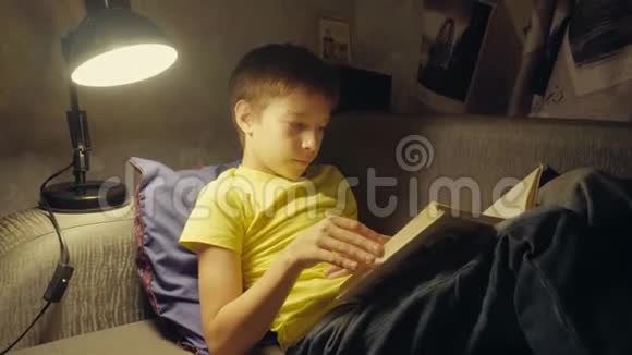 晚上男孩在家沙发上看书视频的预览图