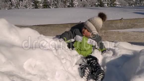 冬天小可爱的男孩在外面的雪地里玩耍背景是一片雪林这个男孩很高兴慢慢视频的预览图
