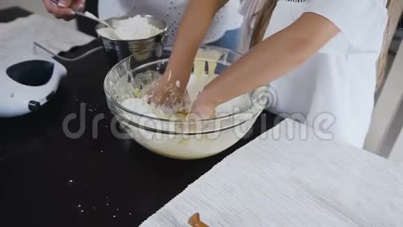 年轻的白种人女孩有妈妈在碗里搅拌面糊母亲和女儿在厨房里烘焙离这里很近视频的预览图