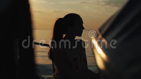 一个扎着马尾辫的漂亮女孩站在一艘旅游船的甲板上望着远方日落时分的河流部分视频的预览图