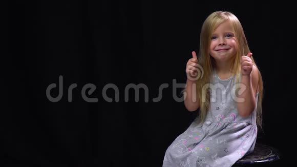 快乐的小女孩竖起大拇指然后看着视频的预览图