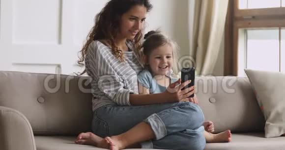 开心的妈妈和小女儿笑着用看电话视频的预览图