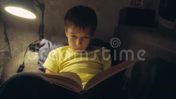 晚上男孩在家沙发上看书视频的预览图