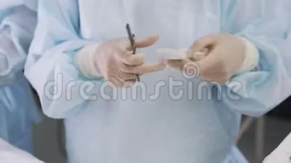 在手术过程中医生双手并拢使用医疗器械夹钳棉签视频的预览图