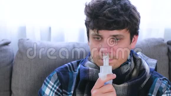 病人通过吸入器喷嘴吸入鼻子坐在沙发上特写面部正面视图使用雾化器视频的预览图