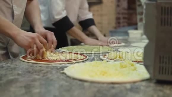 一组厨师以均匀的形式把奶酪放在比萨饼面团圈上视频的预览图