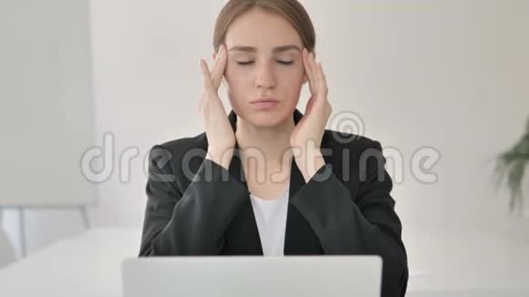 有头痛的年轻女商人在笔记本电脑上工作视频的预览图