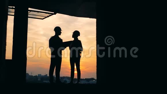 正在建造中的大楼两名工程师站在夕阳下视频的预览图