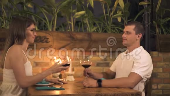 快乐的一对夫妇在浪漫的晚餐上喝红酒在餐馆里点蜡烛男人和女人喝红酒视频的预览图