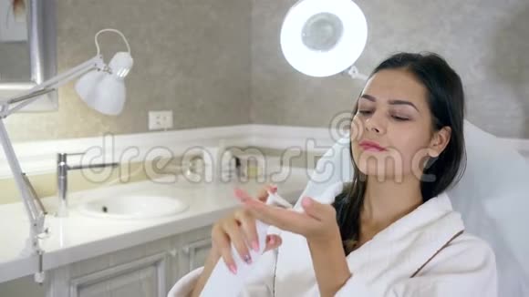 面部皮肤护理美丽的女孩使用保湿面霜躺在美容院的沙发上视频的预览图