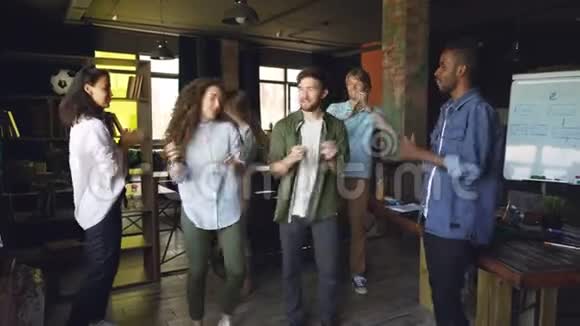 国际公司员工欢乐的同事们正在公司聚会上跳舞庆祝节日的欢笑和欢乐视频的预览图