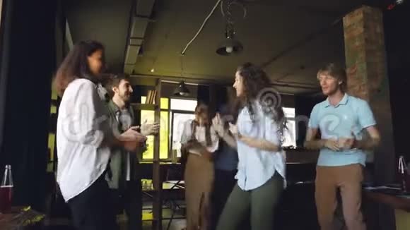 兴奋的年轻男女同事正在跳舞在工作中庆祝胜利办公室乐趣公司视频的预览图