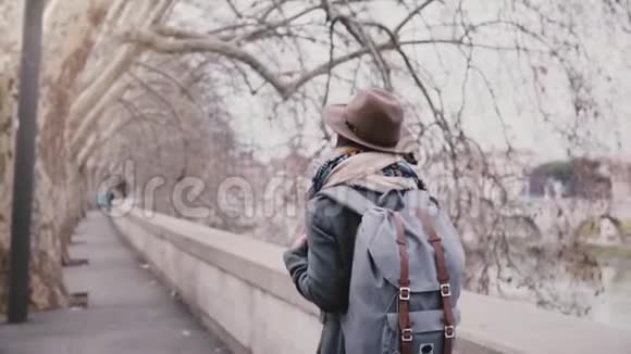 一个美丽的慢动作镜头当地女孩带着背包在锡伯河上的梧桐树下散步在一个冬天的日子视频的预览图