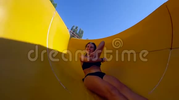 夏天在水上乐园休息年轻女子穿上泳衣在大滑梯上嬉戏玩耍视频的预览图