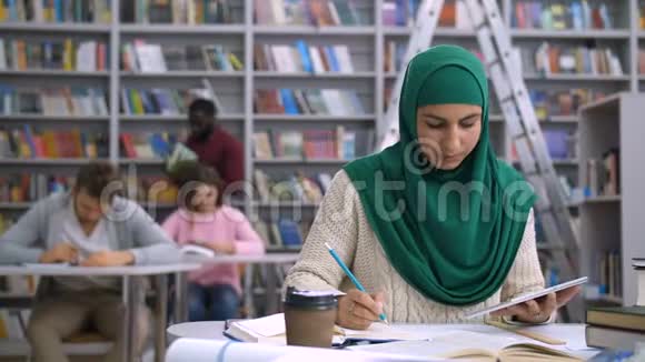 漂亮的穆斯林女学生在图书馆学习视频的预览图