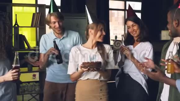 公司的员工都在庆祝生日女人拿着蛋糕吹着蜡烛同事都在拍手视频的预览图