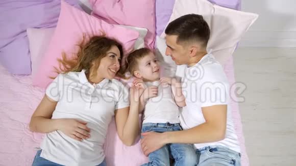 幸福的一家人在床上妈妈儿子和爸爸在一起接吻和拥抱视频的预览图