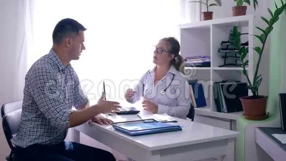 女医生与男性病人交谈并在餐桌上的诊所里出示X线片视频的预览图