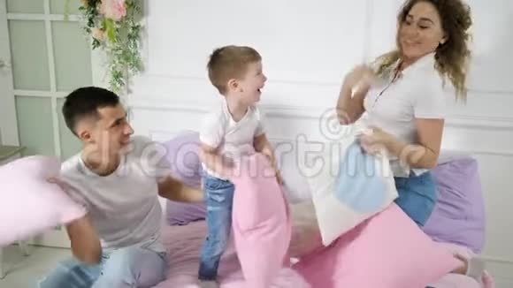 小家庭爸爸妈妈和小儿子在床上玩枕头大战视频的预览图