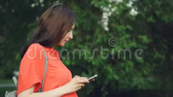 有魅力的孕妇在公园散步使用智能手机人们看着屏幕然后看着视频的预览图