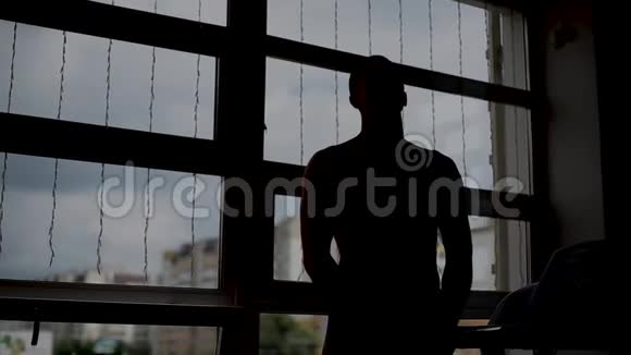 一个男人在健身房的窗户附近摆姿势视频的预览图